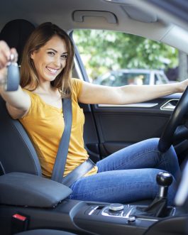 Beautiful female women driver sitting in her vehicle and holding car keys ready for a drive.
