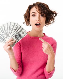 Portrait of an excited pretty girl pointing finger at bunch of money banknotes isolated over white background