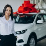Woman by the car with big red bow